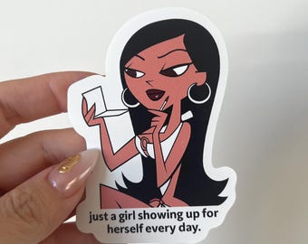 May include: A sticker featuring a cartoon woman with black hair and hoop earrings, holding a compact mirror. The sticker has the text "just a girl showing up for herself every day."