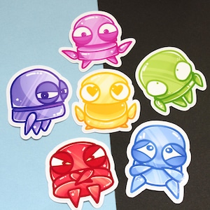 May include: A collection of six colorful cartoon stickers featuring alien-like creatures. The stickers are in shades of pink, purple, yellow, green, red, and blue. Each creature has a unique expression.