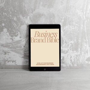 May include: A black tablet computer displaying a digital document titled "Business Brand Bible" with the text "Level Up Your Business and Branding Like a Boss" on a gray textured background.