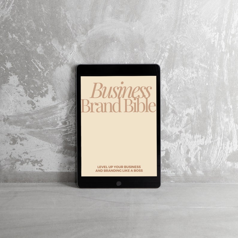 May include: A black tablet computer displaying a digital document titled "Business Brand Bible" with the text "Level Up Your Business and Branding Like a Boss" on a gray textured background.