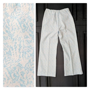May include: A pair of light blue pants with a white floral pattern. The pants have a wide leg and a relaxed fit.