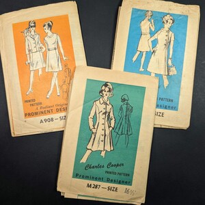 May include: Three vintage paper sewing patterns featuring illustrations of dresses and coats. The orange envelope is labeled A908, the blue envelope is a Prominent Designer pattern, and the teal envelope is labeled Charles Cooper M287 size 16 1/2.