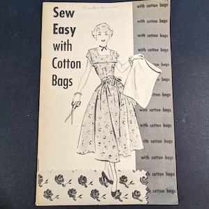 May include: Vintage sewing pattern booklet titled "Sew Easy with Cotton Bags." The cover features a black and white illustration of a woman in a dress, holding a cotton bag and scissors. The background is a dark blue.