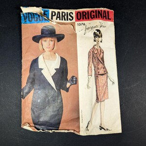 May include: Vintage Vogue Paris Original sewing pattern 1376 by Jacques Heim. The pattern features illustrations of two stylish outfits: a navy blue dress with a white collar and a pink tweed suit. The pattern is on aged paper.