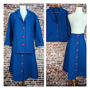 May include: A blue skirt suit with a jacket and skirt. The suit has red buttons and red stitching. The jacket has a collar and long sleeves. The skirt is knee-length and has a button-up front.