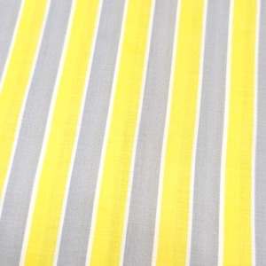 May include: A fabric featuring a repeating pattern of vertical stripes in bright yellow, light gray, and thin white lines. The textile displays a consistent, uniform weave with a smooth texture, showcasing a vibrant color palette throughout the surface.