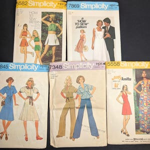 May include: A collection of vintage Simplicity sewing patterns. The patterns feature illustrations of dresses, jumpsuits, and separates. The covers display images of the finished garments, with text including pattern numbers and the phrase "How to Sew Pattern."