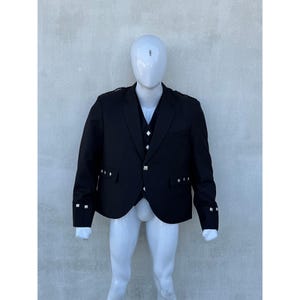 Puede incluir: Una chaqueta negra con botones plateados y un chaleco a juego. La chaqueta tiene cierre de doble botonadura y solapa de muesca.