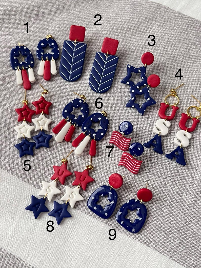 May include: A selection of red, white, and blue earrings with patriotic themes. Designs include star shapes, flag motifs, and geometric patterns. Some earrings feature the letters "USA".