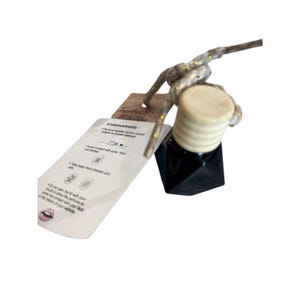 May include: A black, geometric-shaped car air freshener with a light-colored wooden top and a knotted rope. A tag with the text "Turkish Mocha" and announcements is attached.