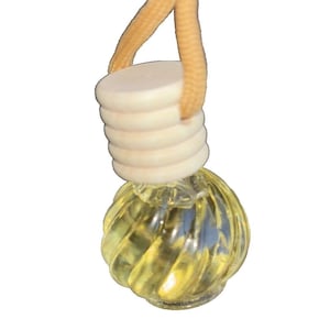 May include: A clear glass aromatherapy diffuser bottle with a spiral design, filled with a yellow liquid. It has a light-colored wooden cap and a tan string for hanging. The bottle is designed for use in a car or small space.
