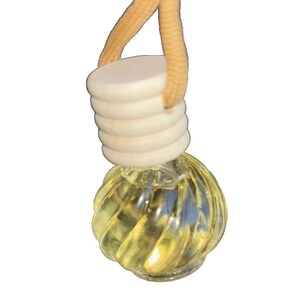 May include: A clear glass aromatherapy diffuser with a spiral design, filled with a yellow liquid. It has a light-colored wooden cap and a tan string for hanging. The diffuser is designed to release fragrance.