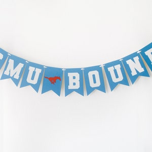 May include: A banner with blue pennants strung together with white string. Each pennant has a white letter, spelling "SMU BOUND". A red mustang logo is on one pennant. The banner is against a white background.