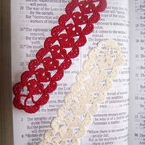 May include: A close-up of an open Bible with two crocheted bookmarks. The red bookmark is on the left side of the page and the white bookmark is on the right side of the page. The Bible text is from Proverbs 10:28.