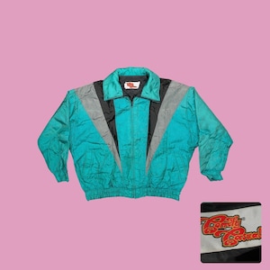 May include: Teal, black, and gray vintage jacket with a full zipper and a collared neckline. The jacket has a color block design with a "Comfy Casual" logo patch. The jacket is a retro style.