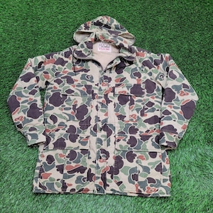 May include: A long-sleeve hooded jacket featuring a camouflage pattern in shades of tan, brown, green, and black. The jacket includes a front zipper closure, two chest pockets with flaps, and two lower pockets with flaps. A Walls brand label is visible.