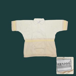 May include: Cream-colored polo shirt with a light yellow stripe across the chest and on the sleeves. The shirt has a collared neckline and short sleeves. The brand tag is visible in the lower right corner. The shirt is made of a soft, comfortable material.