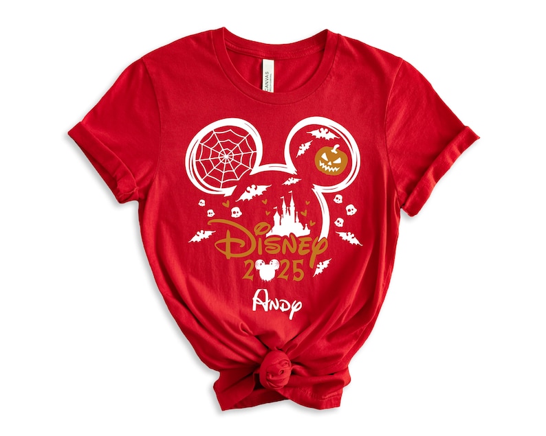 May include: Red t-shirt with a Halloween-themed Disney design. The design includes Mickey Mouse ears with a spiderweb and jack-o'-lantern, bats, a castle, and the text "Disney 2025" with a name below.