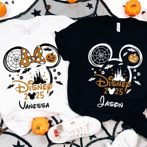 May include: Two Halloween t-shirts, one white and one black, with a Disney-themed design. The design includes Mickey Mouse ears with a spiderweb, pumpkin, castle, bats, and the text "Disney 2025" with a name. The white shirt has a polka-dot bow.