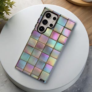 May include: A smartphone case with a colorful, iridescent, mosaic-like design. The case features a grid pattern of small, square tiles in shades of pink, blue, green, and yellow. The phone's camera lenses are visible at the top.