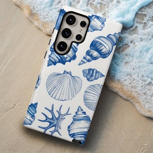 May include: A white phone case with a blue and white seashell pattern. The case has a camera lens cutout and a white background.