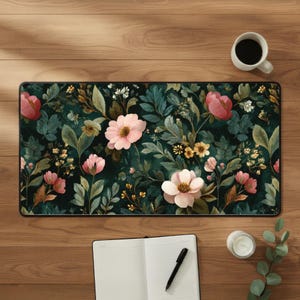 May include: A rectangular desk mat featuring a dark forest green background with a dense botanical pattern of light pink flowers, small yellow blossoms, and various green leaves. The mat has a black border and a smooth, flat surface texture.