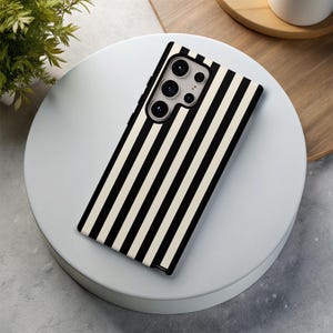 May include: Black and white striped phone case with a camera lens cutout.