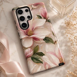 May include: A rectangular smartphone case featuring an oil painting style print of large white and pink magnolia flowers with green leaves. The case has a black camera cutout section with five circular lenses and a black border along the edge.