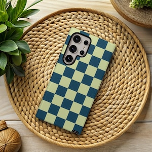 May include: A smartphone case with a blue and light green checkerboard pattern. The case is lying on a woven wicker tray. The phone case has a multi-lens camera system.
