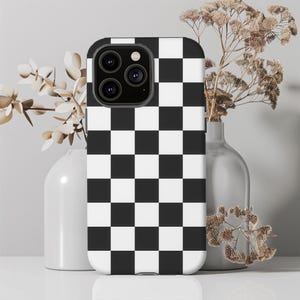 May include: Black and white checkered phone case for an iPhone. The case has a black and white checkered pattern.