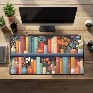 May include: A rectangular desk mat featuring a colorful illustration of a bookshelf filled with books and potted plants. The design includes various colors, such as blue, orange, and white, creating a vibrant and decorative aesthetic. The mat is placed on a wooden desk.
