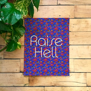 Könnte beinhalten: Ein blauer und roter Poster mit floralem Muster und dem Text "Raise Hell" in Weiß.