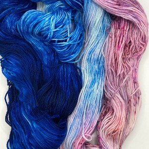 May include: Two skeins of yarn, one blue and one pink, with a gradient of color from dark to light. The yarn is soft and fluffy, and it would be perfect for knitting or crocheting.