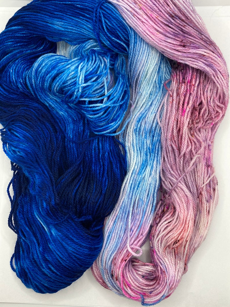 May include: Two skeins of yarn, one blue and one pink, with a gradient of color from dark to light. The yarn is soft and fluffy, and it would be perfect for knitting or crocheting.