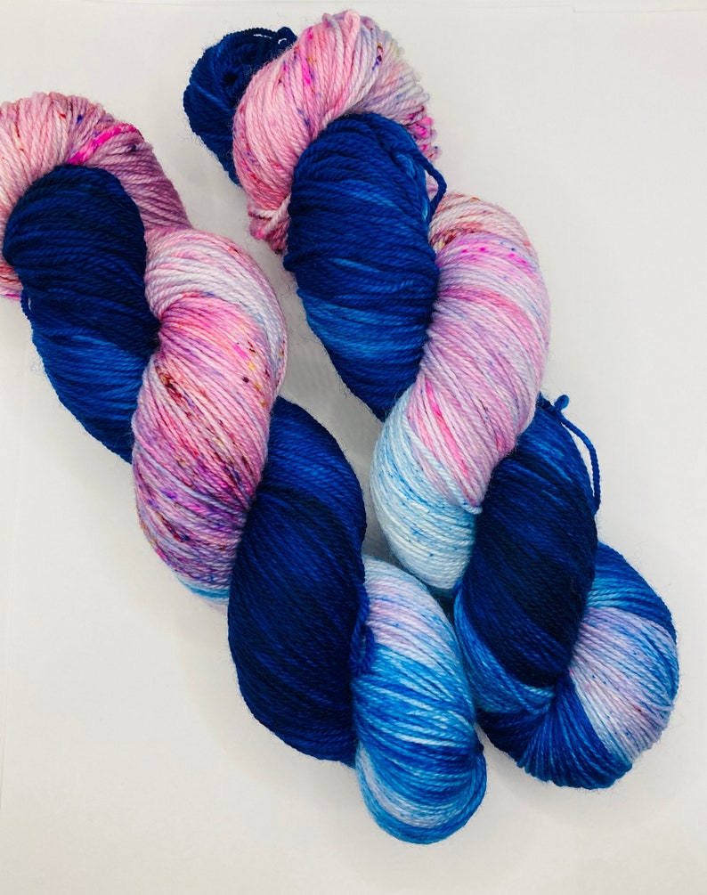 May include: Two skeins of yarn, one blue and white with pink speckles, the other a deep blue with pink and white speckles.