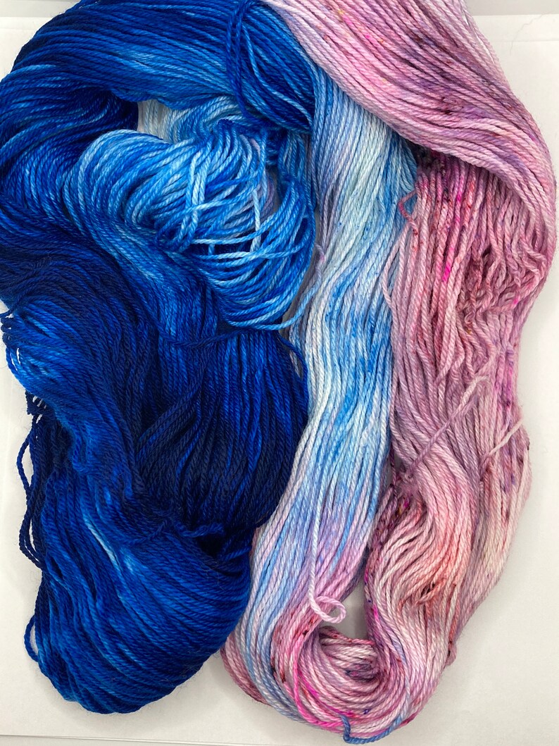 May include: Two skeins of yarn, one blue and one pink, with a gradient of color from dark to light.