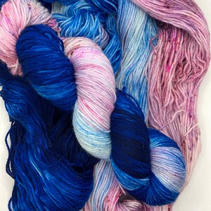 May include: Two skeins of yarn, one blue and one with a pink, white, and blue ombre effect.