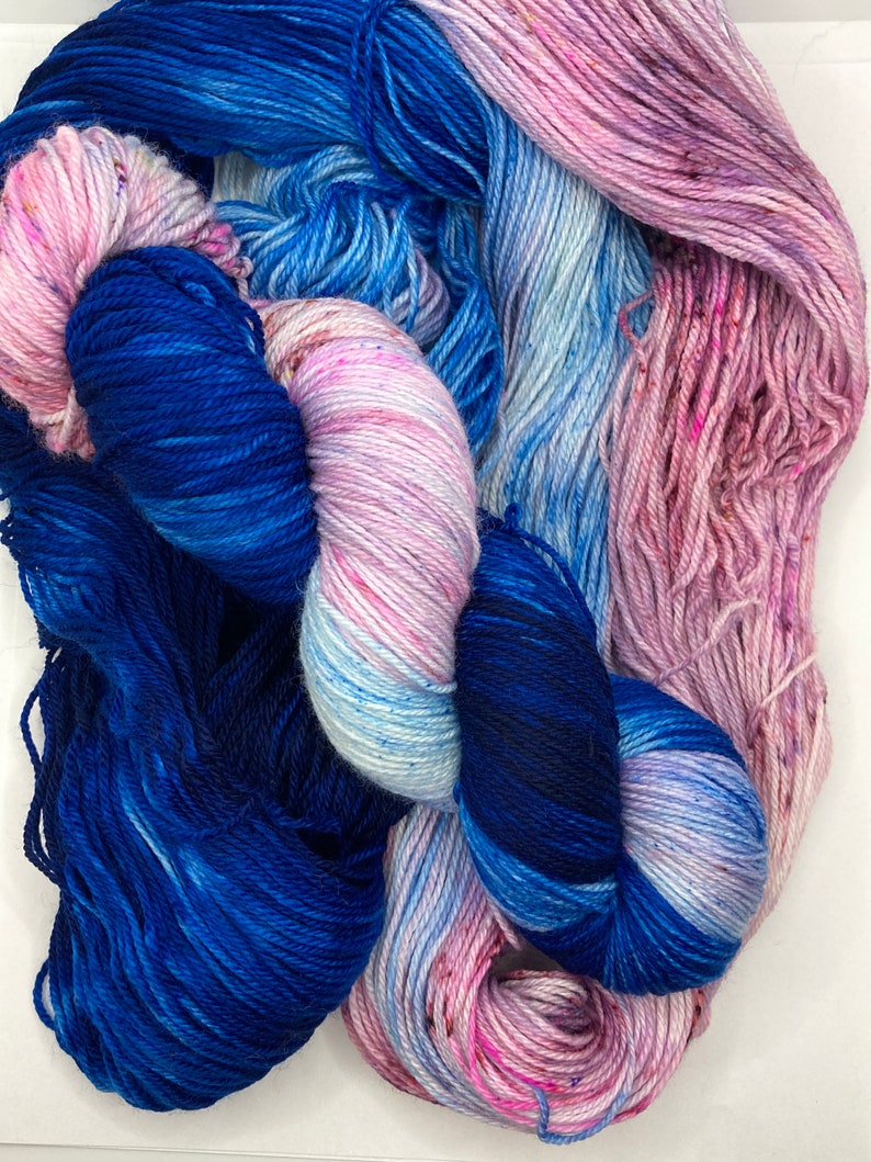 May include: Two skeins of yarn, one blue and one with a pink, white, and blue ombre effect.