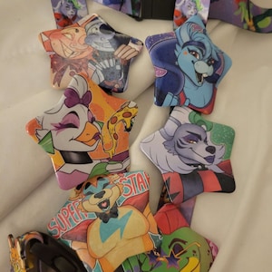 May include: A collection of star-shaped character pins featuring colorful illustrations. The pins are attached to purple lanyards with character designs. The pins showcase various characters with vibrant colors and detailed artwork, perfect for fans of the franchise.