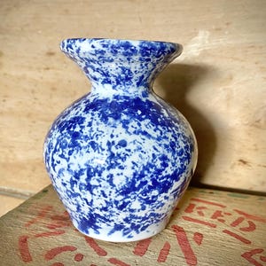 Vaso pequeno vintage de cerâmica esponjosa azul e branca com respingos.