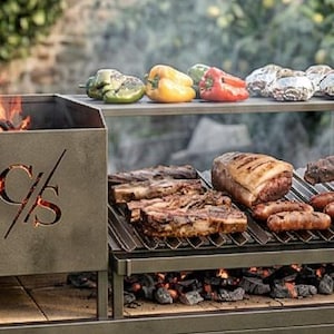 Puede incluir: Una parrilla exterior de acero inoxidable con un fogón y dos estantes. La parrilla está cargada con varios cortes de carne, salchichas y verduras. Una persona usa pinzas para manipular la comida. La parrilla está en un jardín.