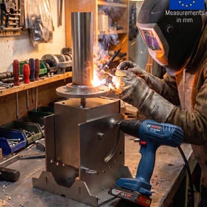 May include: A metal welding project featuring a cylindrical pipe attached to a square base, being worked on by a person in a welding helmet and gloves. A blue Bosch 18V cordless drill is positioned next to the metal structure on a workbench.