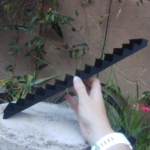 Op de afbeelding: Zwarte plastic miniatuurtrap met 10 treden. De trap is ongeveer 30 cm lang.