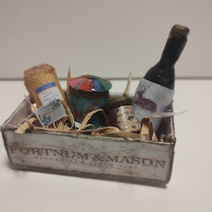 May include: A wooden box with the words "Fortnum & Mason Piccadilly Since 1707" printed on the side. The box contains a bottle of wine, a jar of jam, a tin of biscuits, and a package of food.