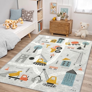 Könnte beinhalten: Ein grauer Kinderteppich mit einem Baustellenthema. Der Teppich zeigt Illustrationen von Baufahrzeugen, Gebäuden, Bäumen und Straßenmarkierungen in Gelb, Orange, Blau und Schwarz. Der Teppich ist rechteckig.