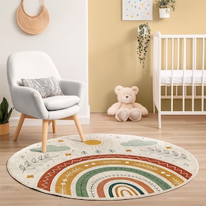 Pode incluir: Um tapete redondo com um design de arco-íris em tons de laranja, verde e amarelo. O tapete apresenta um sol, nuvens e elementos botânicos. Está colocado sobre um chão de madeira, com uma cadeira branca e um berço no fundo.