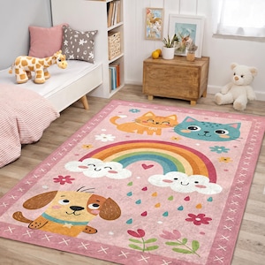 May include: Pink rectangular rug with a cartoon design featuring a rainbow, smiling clouds, a dog, and two cats. The rug has a border with an X pattern and is designed for a child's room.