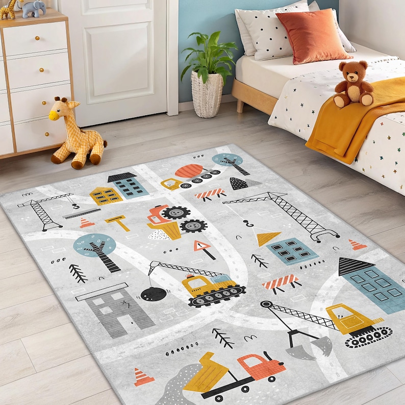 May include: A grey children's rug with a construction theme. The rug features illustrations of construction vehicles, buildings, trees, and road markings in various colours. The design includes a dump truck, excavator, and crane.