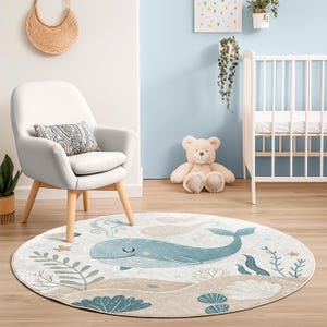Non-slip round rug for children showing an illustrated whale swimming above coral and shells, ideal for a cozy play area.