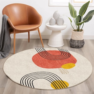 May include: A round, cream-colored rug with a geometric design featuring black, red, and yellow shapes. The rug has a subtle texture and a fringe border.